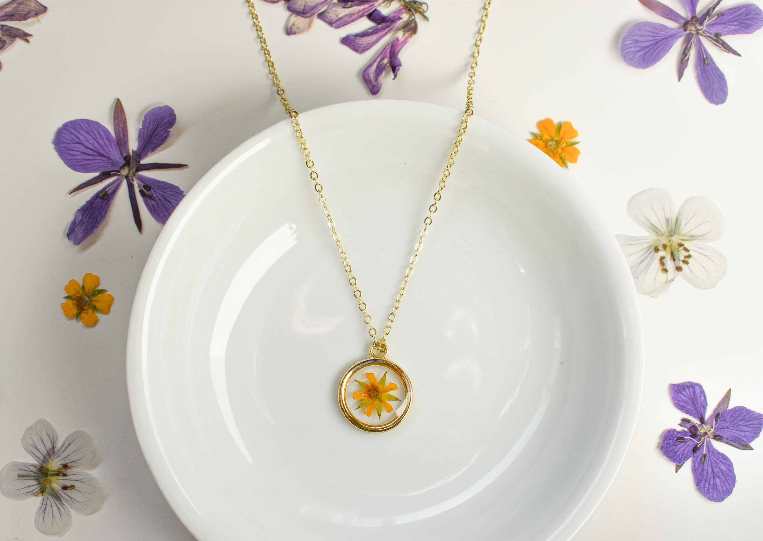 A necklace with wedding flowers for a bridal gift. Handmade gift for brides made out of resin and pressed flowers.