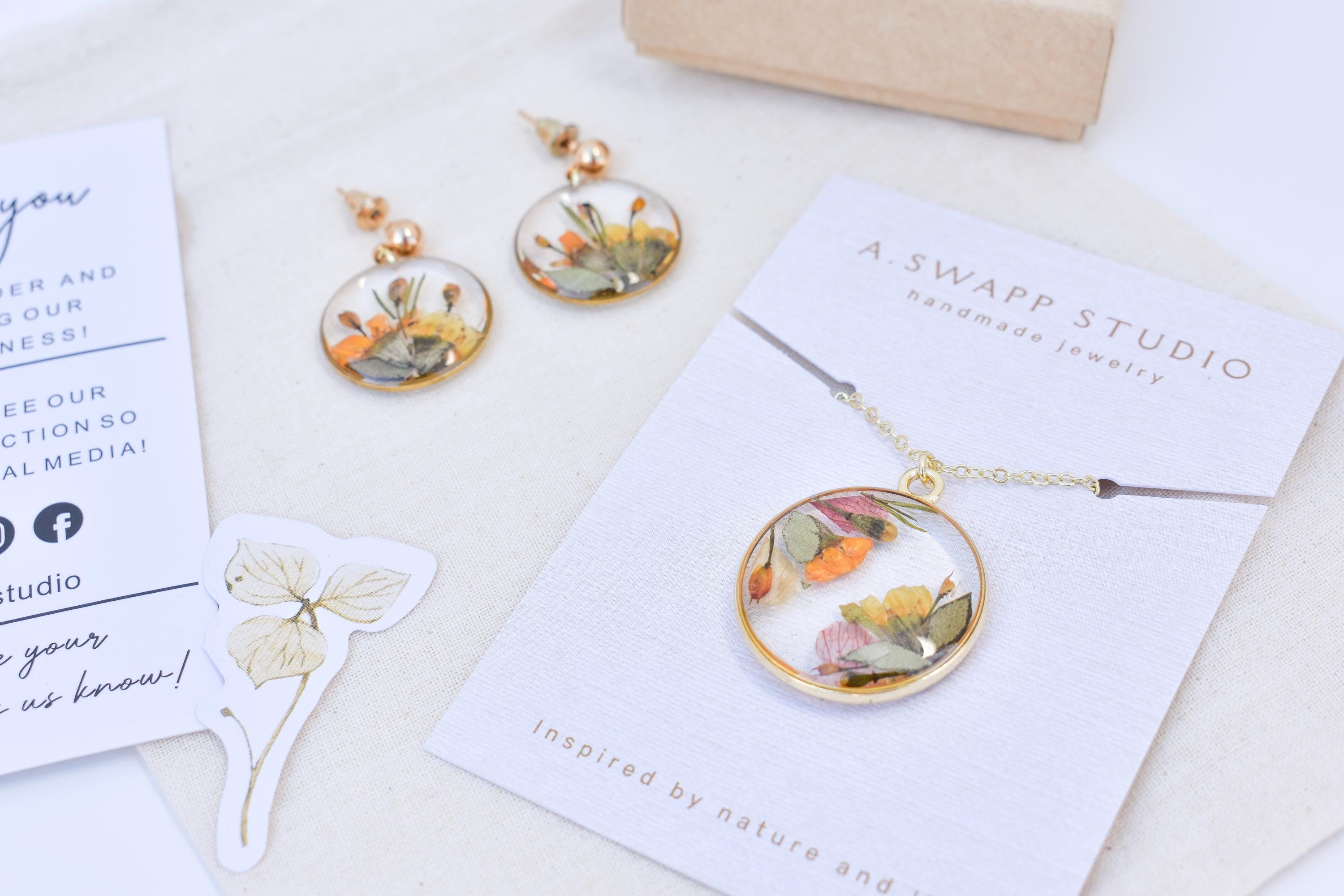A necklace with wedding flowers for a bridal gift. Handmade gift for brides made out of resin and pressed flowers.
