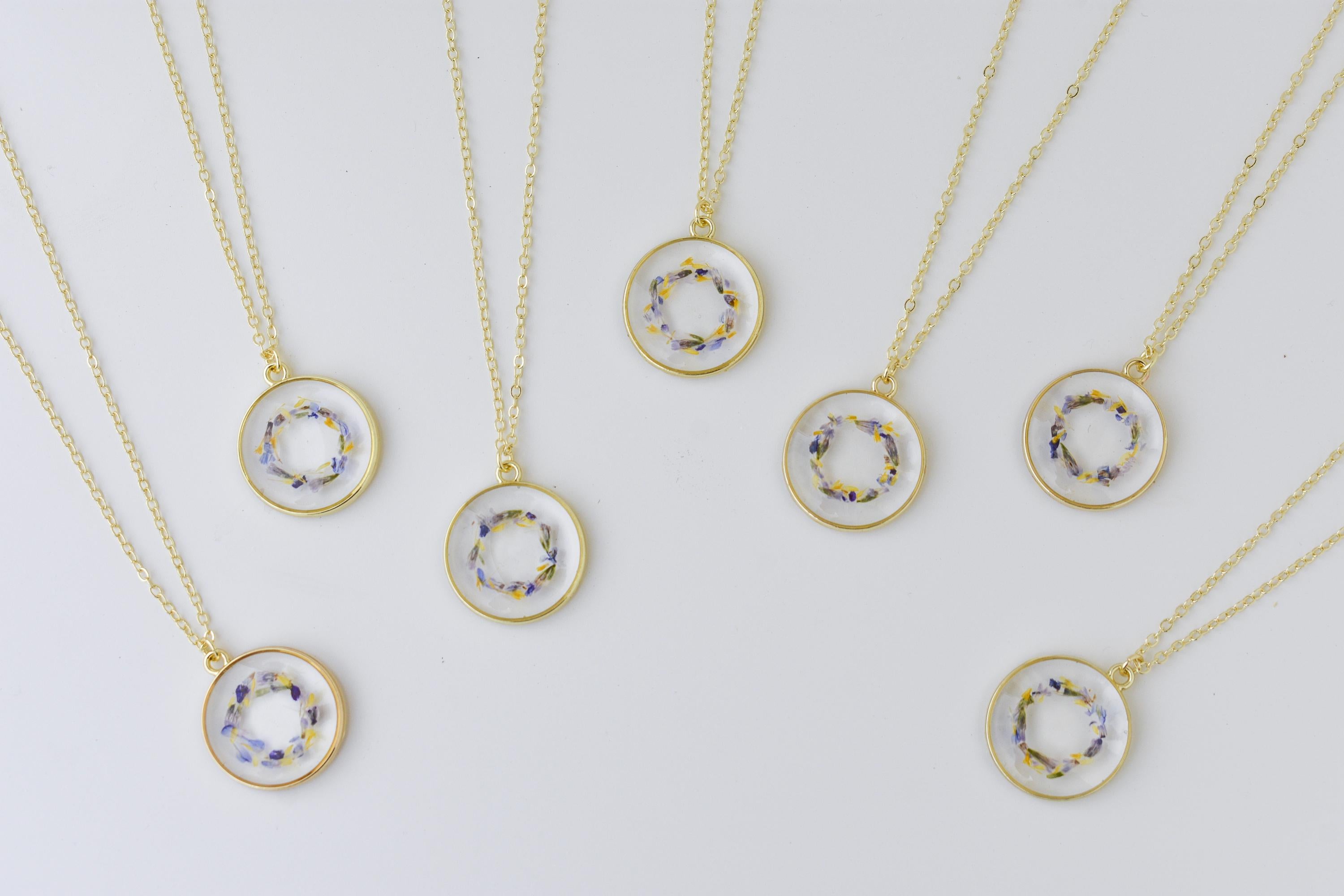 A necklace with wedding flowers for a bridal gift. Handmade gift for brides made out of resin and pressed flowers.